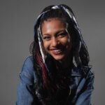 Una joven morena cn trenas sonríe ante la cámara.